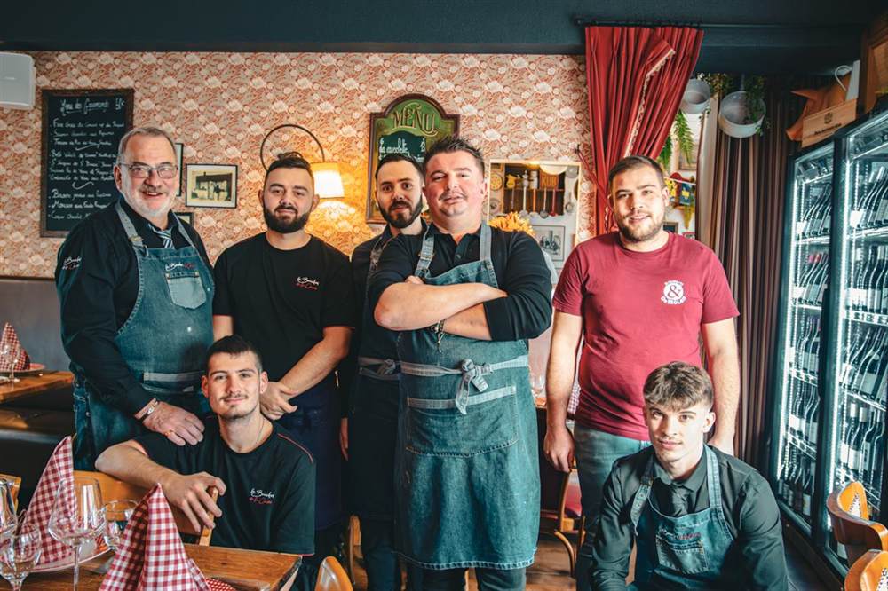 L'équipe du Bouchon de la Cave réunie en salle, tabliers de la maison, devant l'ardoise des gourmandises
